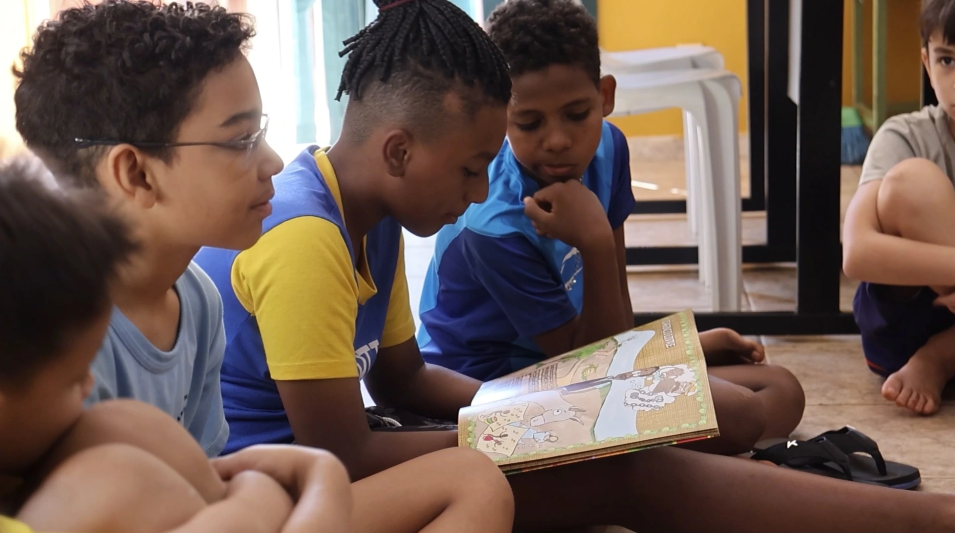 Crianças lendo um livro juntas em roda no CPTI