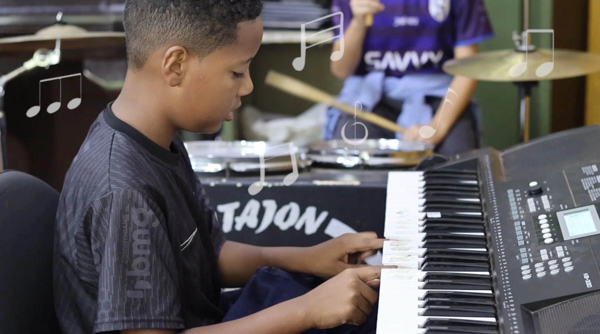 Menino tocando teclado em aula de música do CPTI
